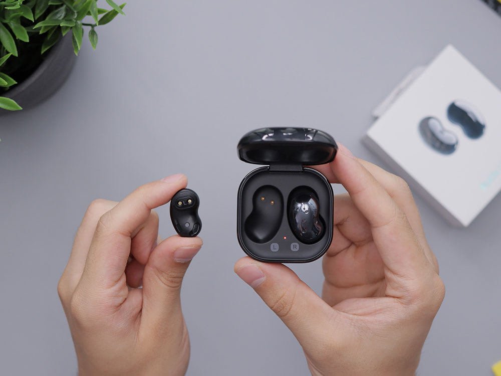 hands holding headphones and headphone charger box